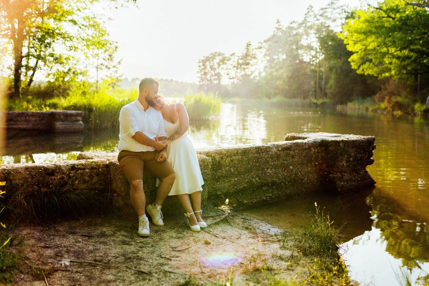 Couple en séance engagement à la Jemaye assis sur un muret