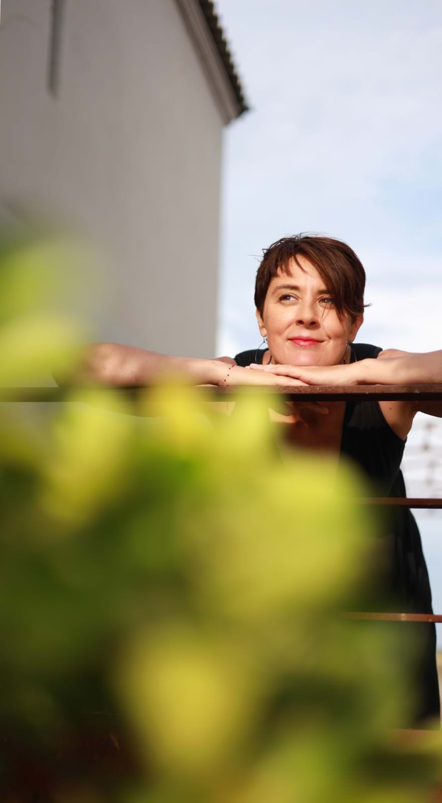 Personne souriante appuyée sur une rambarde.