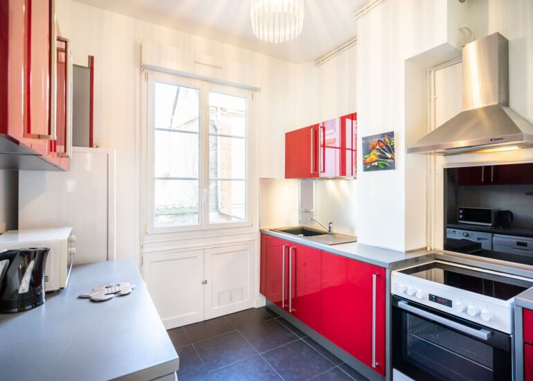 Cuisine rouge et blanche équipée, espace commun pour les repas pendant l’atelier photo-thérapie.