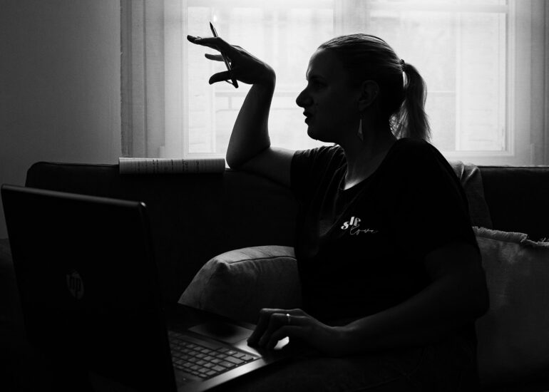 Portrait en noir et blanc d’une participante en pleine réflexion, assise devant un ordinateur pendant l’atelier photo-thérapie.