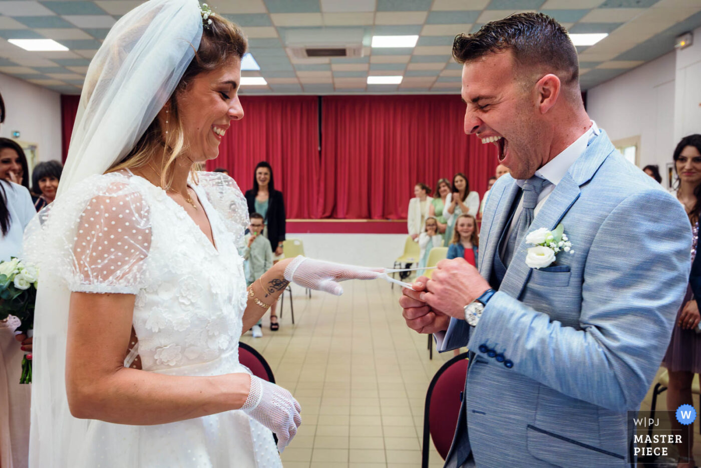 Mariés en train d’échanger les alliances en riant pendant la cérémonie de mariage à la mairie