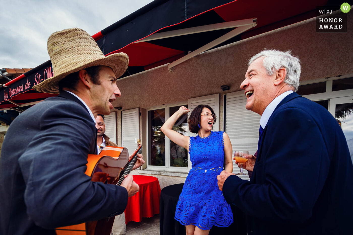 Invité jouant de la guitare et faisant rire les autres invités pendant le cocktail de mariage en extérieur
