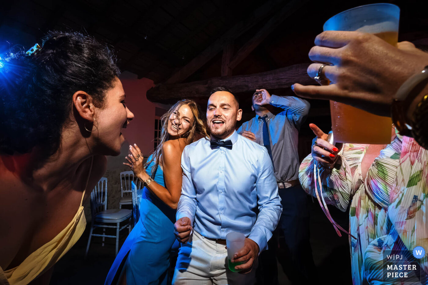 Invités dansant et chantant sur la piste lors d’une soirée de mariage avec lumière colorée